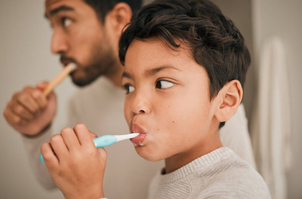 Tvář, chlapec a dítě čistí zuby s otcem pro hygienu, ranní rutinu nebo rozvoj zdravé ústní péče doma. Kid, táta a zubní kartáček na čištění zubů, čerstvý dech nebo ústa v koupelně. - Fotografie, Obrázek