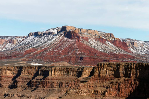 Uppoudu Grand Canyonin talvimaailmaan tämän korkean resoluution valokuvan kanssa, jossa on lumisia huippuja vaaleansinisen taivaan alla. Kuva vangitsee harvinainen hetki, jolloin ikonin punainen - Valokuva, kuva