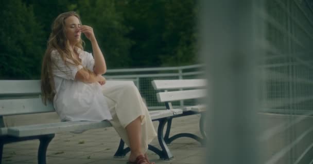 Plan au ralenti d'une jeune femme désespérée avec la main sur la bouche assise sur un banc - Séquence, vidéo