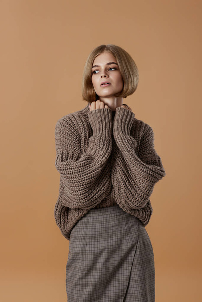 beautiful blonde woman in brown knitted sweater on beige background. autumn style - Фото, изображение