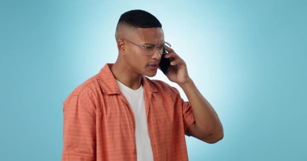 Phone call, communication and angry man talking in studio isolated on a blue background mockup space. Smartphone, chat and serious African person in discussion, listening to bad news and conversation. - Footage, Video