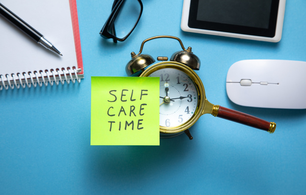 Self care time on sticky note with a clock and business objects. - Photo, Image