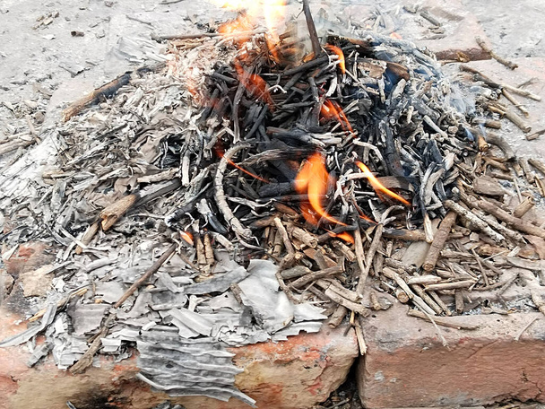 Piękne zdjęcie pojedynczego ogniska z zaciętymi płomieniami koloru żółtego i pomarańczowego przedstawiającymi niepełne spalanie drewna opałowego, podpalonego w sezonie zimowym, aby utrzymać ciepłe otoczenie. - Zdjęcie, obraz