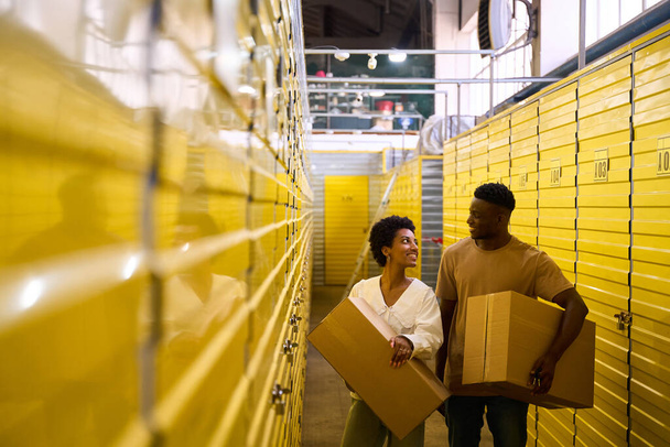 Afro-americano cara e namorada com caixas de papelão, eles alugam uma unidade de armazenamento - Foto, Imagem