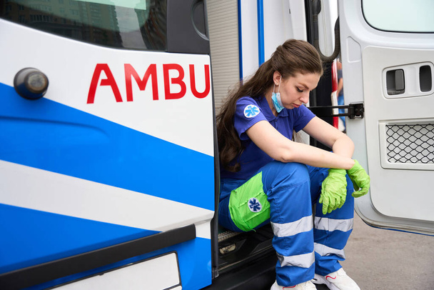 疲れた救急隊員が救急車の足台に座り 医療服を着た女性が - 写真・画像