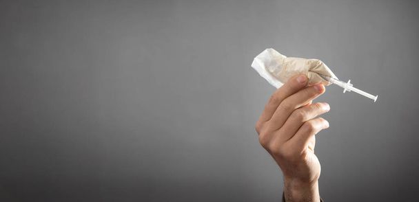 Mão masculina mostrando seringa e pacote de plástico de heroína. - Foto, Imagem