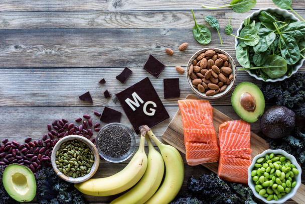 Een assortiment van voedingsmiddelen hoog in magnesium met het element symbool MG voor Magnesium op de chocolade en kopieer ruimte boven. - Foto, afbeelding