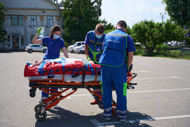 Досвідчені парамедики поклали пацієнта на вакуумний матрац для транспортування до лікарні - Фото, зображення