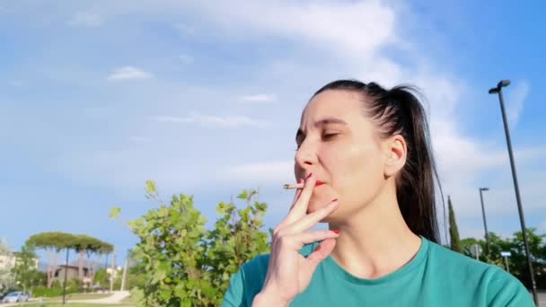 駐車場で太陽の下でタバコを吸っている間に女の子が見えるビデオが紹介されました - 映像、動画