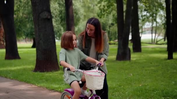 muotokuva perhe nuori äiti opettaa tytär ajaa pyörällä kaupungin puistossa käsite onnellinen lapsuus ja hoito - Materiaali, video