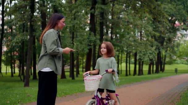 rodina mladá matka hubuje dceru v parku, protože rychlá jízda na kole zlobivé dítě pláče - Záběry, video