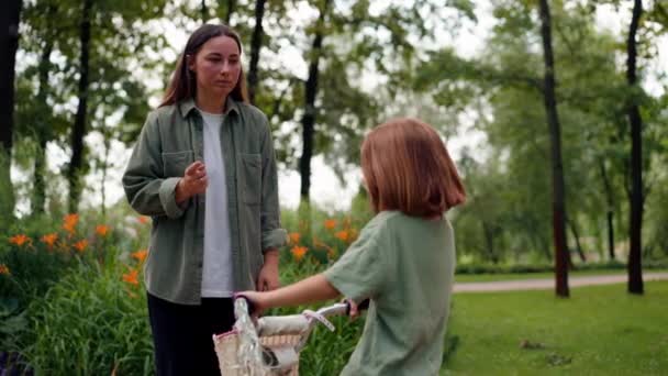 Familie junge Mutter schimpft Tochter im Park für radelndes ungezogenes Kind hört ihr aufmerksam zu - Filmmaterial, Video