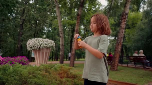 ritratto bello carino bambina soffiando sapone bolla in città parco felice spensierata infanzia - Filmati, video