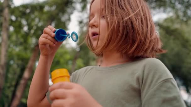 portret mooi schattig klein meisje blazen zeep zeepbel in stadspark gelukkig zorgeloos jeugd - Video