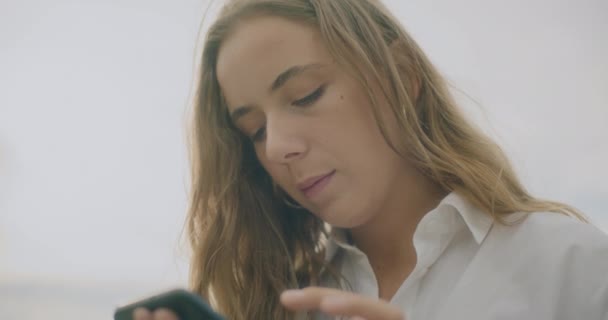 Zeitlupenaufnahme einer jungen schönen Frau, die per Handy SMS verschickt - Filmmaterial, Video