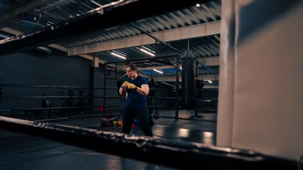 ritratto di una pugile concentrata in bendaggi gialli che colpisce un avversario immaginario in palestra prima della lotta - Filmati, video