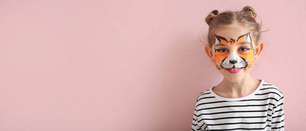 Grappig klein meisje met gezicht schilderen op roze achtergrond met ruimte voor tekst - Foto, afbeelding