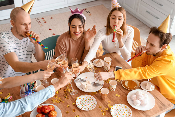 Fiatal barátok csoportja pezsgővel ünnepli születésnapját a konyhában - Fotó, kép