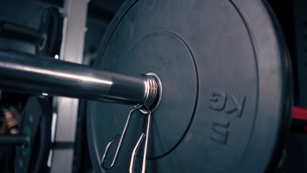 primer plano atleta entrenador añade peso a la barra en el gimnasio aumenta la carga sobre el cuerpo del culturista - Metraje, vídeo