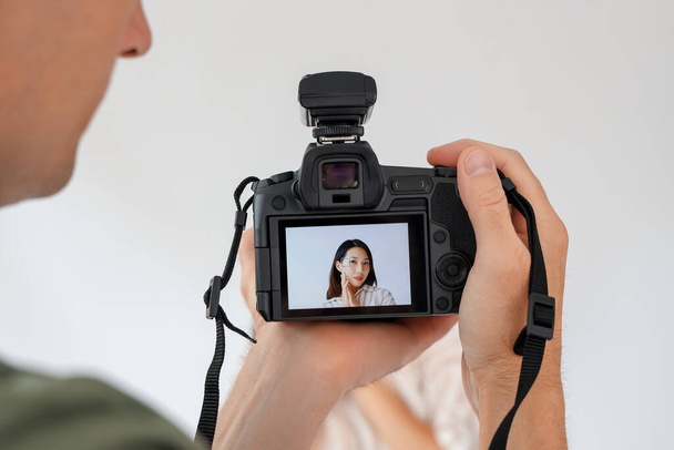 Hombre fotógrafo tomando la foto de la joven mujer asiática en estudio, primer plano - Foto, imagen