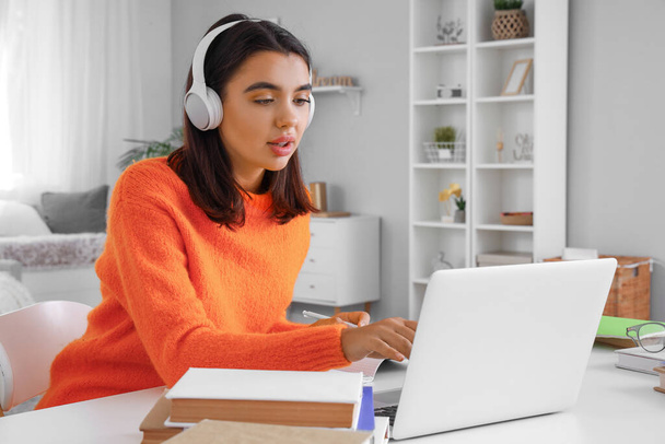 Mujer joven en auriculares aprendiendo inglés en línea en casa - Foto, imagen