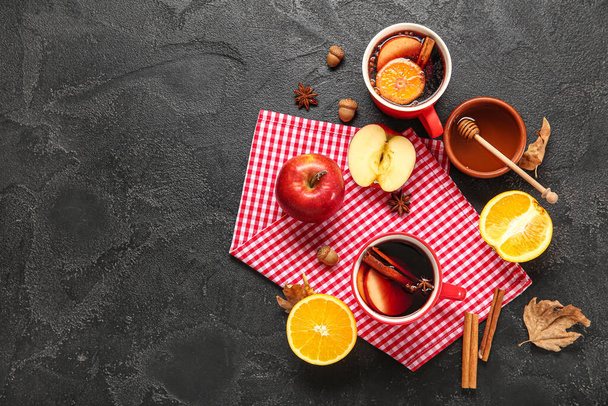 Чашки горячего глинтвейна с яблоком и апельсином на черном фоне - Фото, изображение