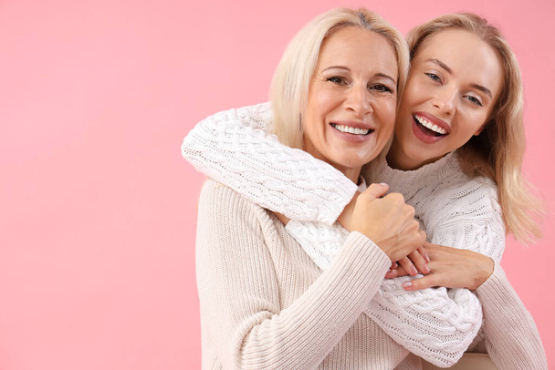gelukkig jong mooi vrouw met haar moeder op roze achtergrond - Foto, afbeelding