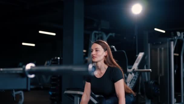 Vücut geliştirme müsabakasında ellerindeki dambıllarla egzersiz yapan konsantre fitness kadın antrenörü. - Video, Çekim