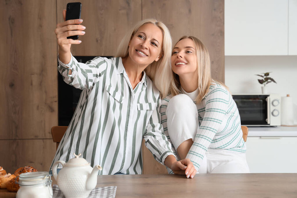 Hermosa joven y su madre tomando selfie en la cocina - Foto, imagen