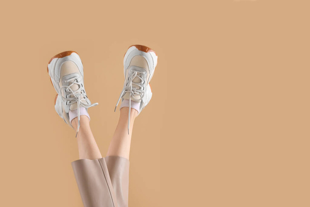 Woman wearing pair of new stylish sneakers on beige background, closeup. Space for text - Photo, Image