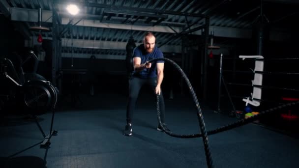 jonge mannelijke bodybuilder doet oefeningen met touw in de handen in de sportschool voorbereiding bodybuilding concurrentie motivatie - Video