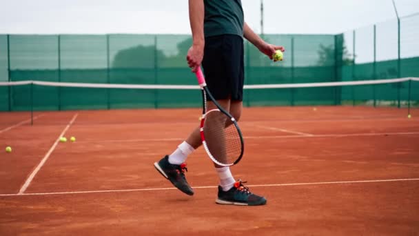 Açık hava tenis kortunun genç profesyonel oyuncu koçu raket tenis topuyla vuruşlar yapıyor. - Video, Çekim