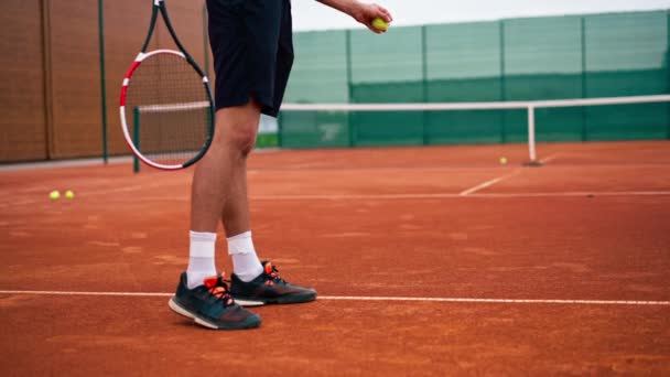 Крупный профессиональный тренер по теннису на открытом воздухе практикует удары ракетным теннисным мячом - Кадры, видео