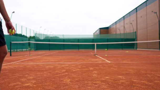 Крупный профессиональный тренер по теннису на открытом воздухе практикует удары ракетным теннисным мячом - Кадры, видео