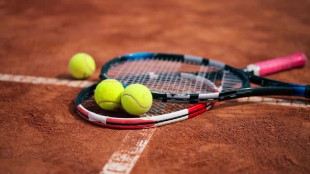 primer plano de los equipos deportivos raquetas de tenis y pelotas se encuentran una cancha de tierra al aire libre hobby competición deporte - Metraje, vídeo