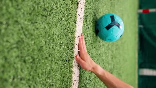 vertikale Video-Nahaufnahme einer Hand, die über einen Fußball-Kunstrasen mit gummierter Textur läuft - Filmmaterial, Video