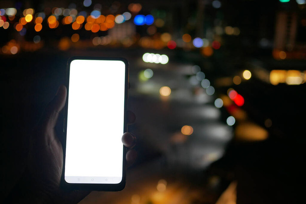 Zbliżenie męskiej dłoni przy użyciu smartfona w nocy . - Zdjęcie, obraz