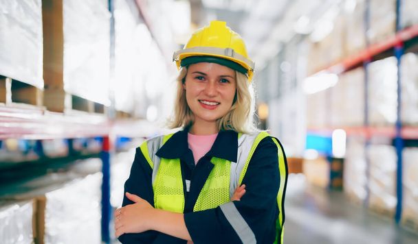 Молодая женщина счастлива стоя и глядя в камеру. Женщина-работница склада смайлик и умный уверенный в себе на складе - Фото, изображение