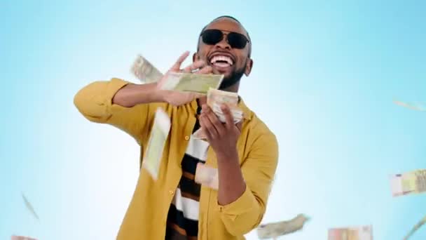 Black man, money rain and finance, happy with winning or bonus, reward and wealth on blue background. Cash, success and financial freedom with prize, cashback and portrait of lotto winner in studio. - Footage, Video