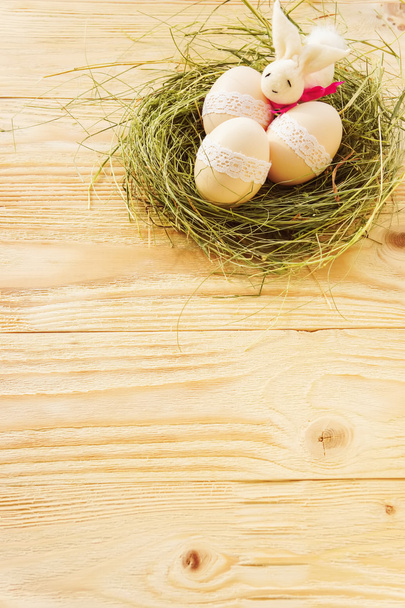 Ostereier und Hase im Nest auf Holztisch - Foto, Bild