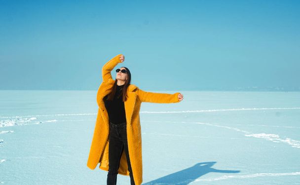 donna in cappotto giallo si diverte sul ghiaccio innevato, concetto di libertà - Foto, immagini