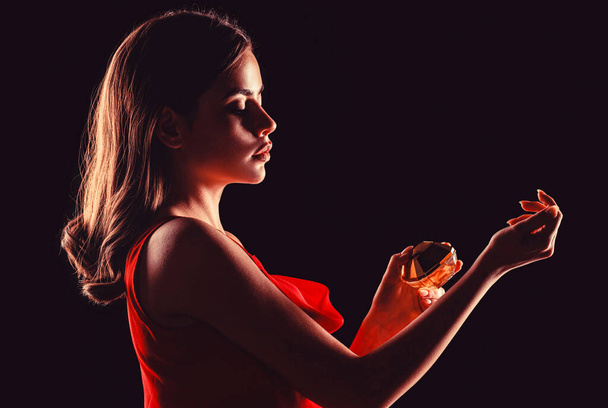 Egy nő egy üveg parfümmel. Parfüm palack nő spray aroma. Egy nő parfümös üveggel a kezében. A nő parfümöket terjeszt. - Fotó, kép