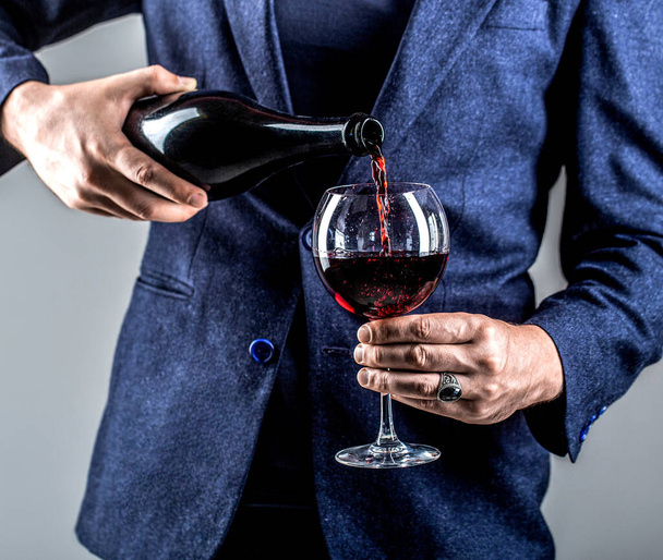 Waiter pouring red wine in a glass. Sommelier man, degustation, winery, male winemaker. - Photo, Image