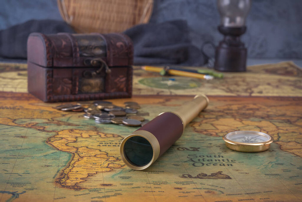 Spyglass a kompas leží na staré mapě na pozadí kované truhly s mincemi. Detailní záběr - Fotografie, Obrázek