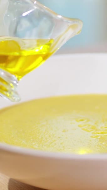 Vertikální video. Ženská ruka nalévá olivový olej do horké smetanové polévky ze skleněného kelímku. Vaření a servírování první chod. - Záběry, video