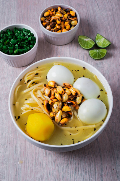 Tradycyjne peruwiańskie danie z rosół z trzema jajkami, makaronem, trzema jajkami, cancha serrana i jej akompaniamentem cytrynowym, chińska cebula. - Zdjęcie, obraz
