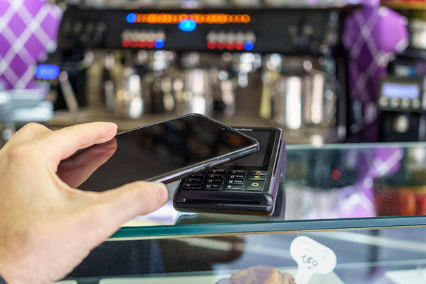 Contactloze betaling per smartphone. Betaling met NFC-technologie in een betaalterminal van een cafetaria. tpv. - Foto, afbeelding