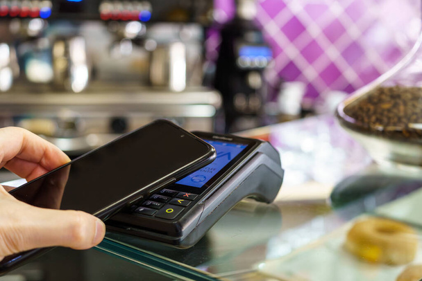 Érintésmentes fizetés okostelefonon keresztül. Fizetés NFC technológiával egy kávézó fizetési termináljában. tpv. - Fotó, kép