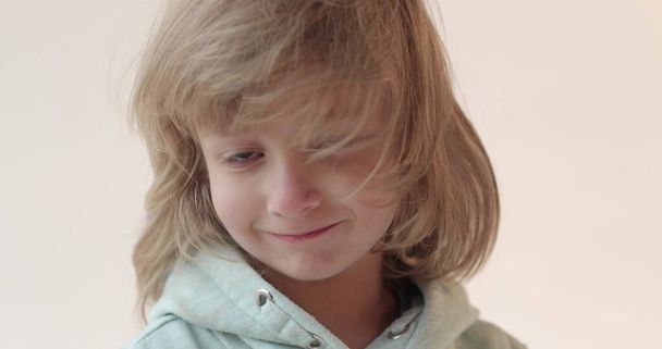 Retrato de estúdio de um menino bonito sorridente com cabelos longos em um terno azul em um fundo branco. Giros e tremores de cabelo Humor infantil positivo. - Foto, Imagem