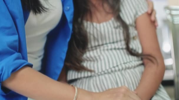 Vrouw houdt haar zieke dochters hand in afwachting van arts in de hal van de kliniek - Video